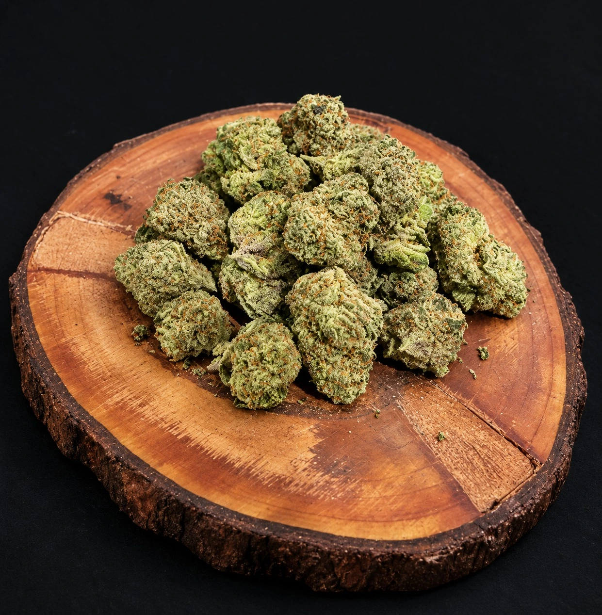 cannabis flower on top of a round wooden tray .